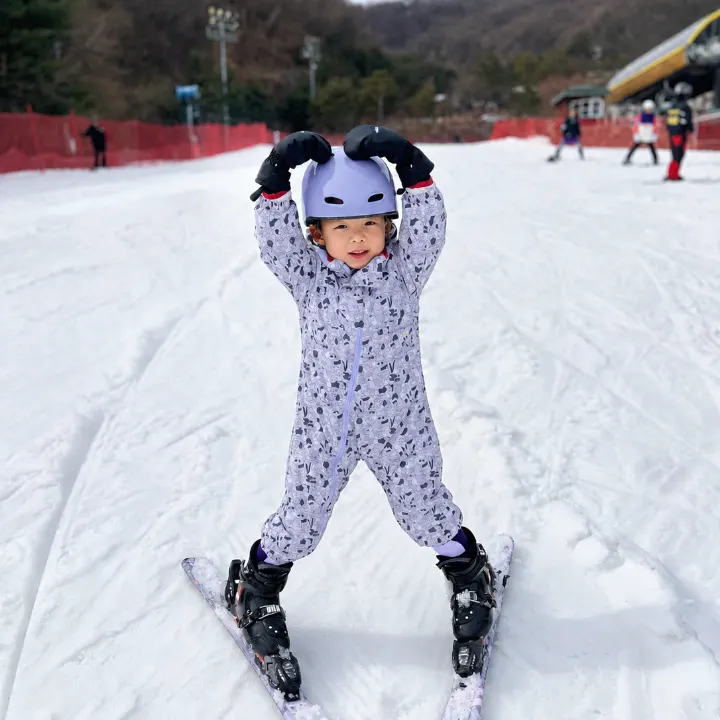 슬로프에서 두 팔로 머리 위에 동그라미를 만든 아이